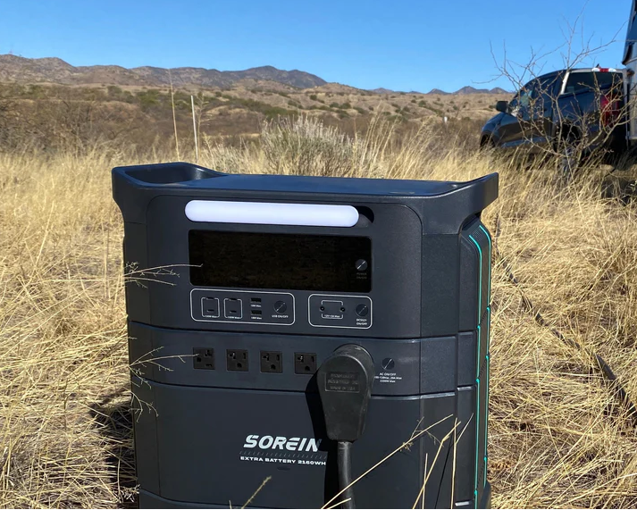 Portable power station in a desert setting with vehicles in the background